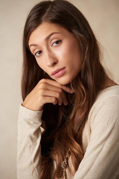 Attractive pensive woman with long healthy hair looking at camera