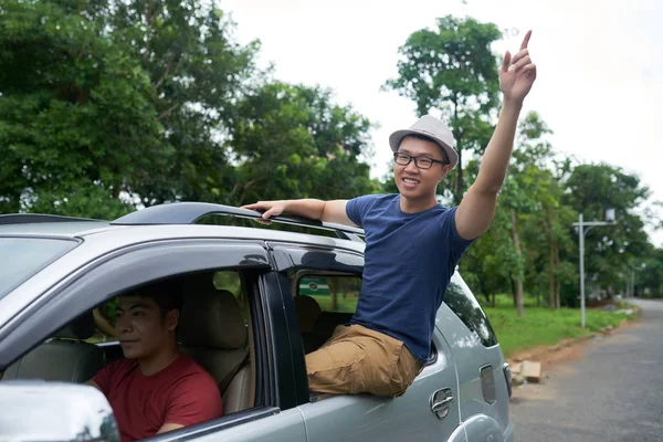 Joven Alegre Con Mano Levantada Inclinándose Por Ventana Mientras Guapo — Foto de Stock