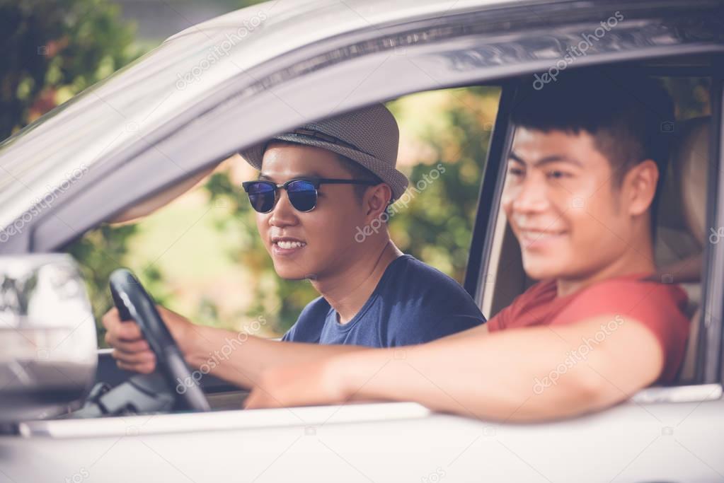 Profile view of smiling Vietnamese tourists having fun in car, road trip