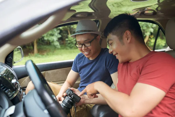 Uśmiechający Się Przystojny Men Razem Siedzi Samochodzie Przeglądając Zdjęcia Profesjonalnych — Zdjęcie stockowe