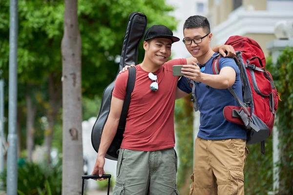 美しい街を歩きながらスマート フォンで Selfie を取って広い笑顔でハンサムな若い観光客 — ストック写真