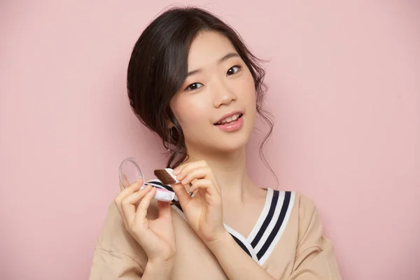可爱的韩国妇女应用腮红 孤立的粉红色 — 图库照片