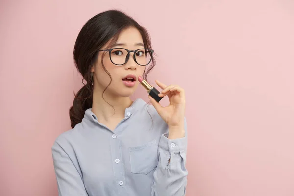 Wanita Cantik Berkacamata Mengaplikasikan Lipstik Terisolasi Pada Warna Pink — Stok Foto