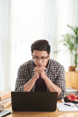 Dalgın Vietnam öğrenci dizüstü bilgisayar ekranında bir şey okuma