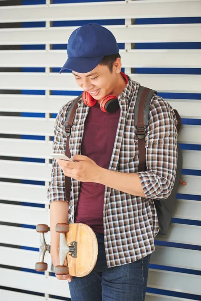 Asiatico Ragazzo Con Skateboard Sorridente Quando Lettura Messaggio Smartphone — Foto Stock