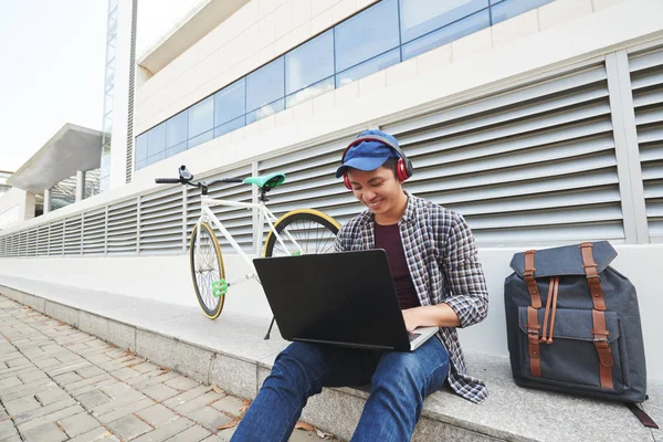 Chico Feliz Con Auriculares Sentados Aire Libre Trabajando Ordenador Portátil —  Fotos de Stock