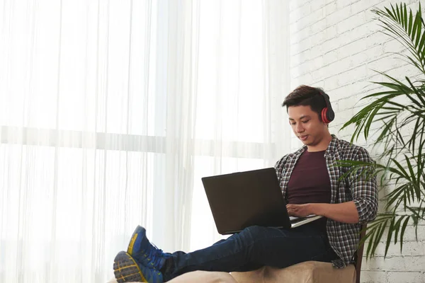 若い男が 自宅でコンピューティングのヘッドフォンで — ストック写真