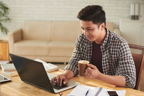 Wesoły Wietnamski Student Picia Kawy Działa Laptopie Domu — Zdjęcie stockowe