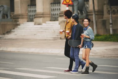 Buzlu çay karşıdan karşıya şehir merkezinde geçerken elinde plastik bardak ile neşeli genç arkadaşlar