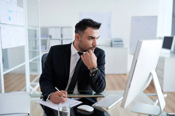 Professioneller Geschäftsmann Schreibt Plan Auf Papier Und Schaut Auf Computermonitor — Stockfoto