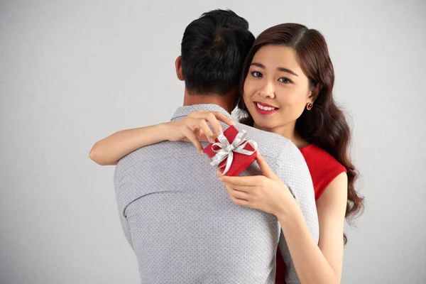 魅力的なアジアの女性の手の中の小さなギフト ボックス彼氏を優しく受け入れながら魅力的な笑顔でカメラ目線 — ストック写真
