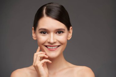 Gülümseyen genç kadın kameraya bakarak, gri izole