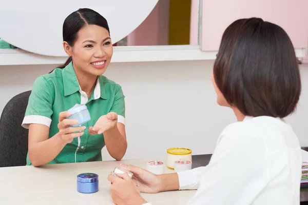 Ganska Vietnamesiska Kosmetolog Visar Grädde Till Ung Kvinna — Stockfoto