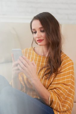 Genç kadın okuma mesajları onun smartphone üzerinde gülümseyen