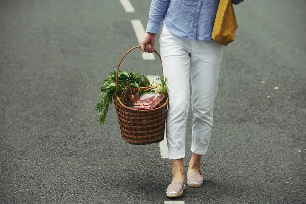 新鮮な有機野菜の大きなバスケットが付いている通りで歩いている女性 — ストック写真