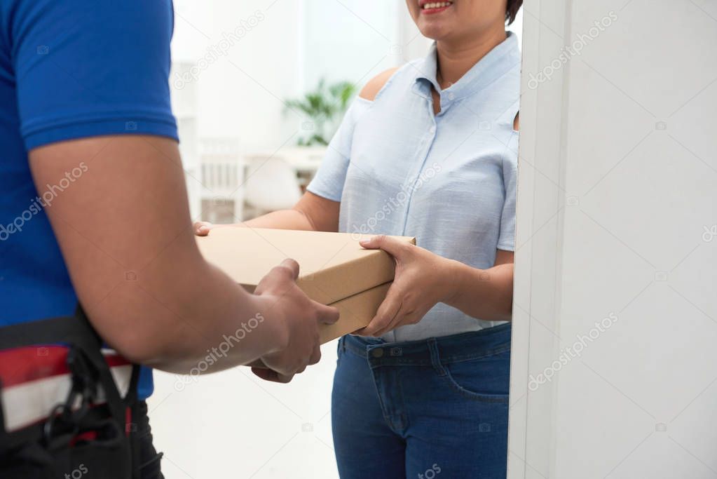 Cropped image of courier giving pizza boxes to woman