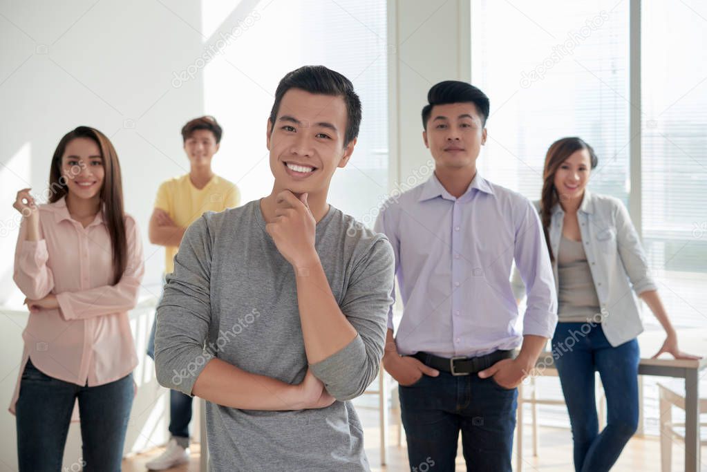 Group of joyful Asian young people, focus on handsome man