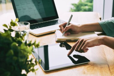 Notlar günlüğüne yazma ve dizüstü bilgisayar ile masada dijital tablet kullanarak kişi
