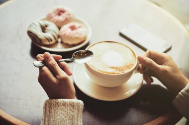 Kısmi kokulu cappuccino ve lezzetli çörekler masada otururken kadının görünümünü