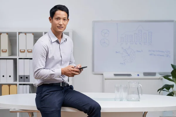 Junger Vietnamesischer Unternehmer Mit Smartphone Der Hand Tisch Sitzend — Stockfoto