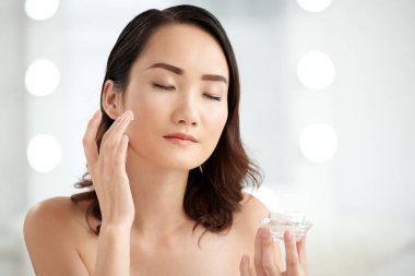 Uygulama Çinli genç kadın Nemlendirici yüzünü zenginleştirilmiş.