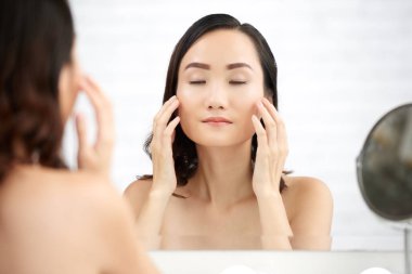 Güzel genç kadının yüzünde nemlendirici uygulanması