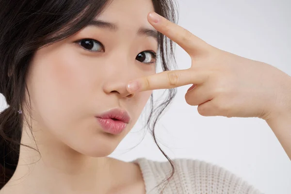 面对迷人的韩国女人与完美的皮肤 女孩打手势用两个手指 — 图库照片