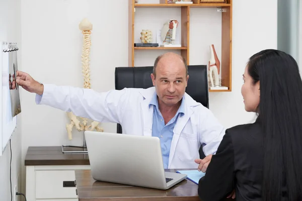 Osteopath consulting female patient in his office — Stock Image Osteopath Consulting Female Patient His Office Stock Photo