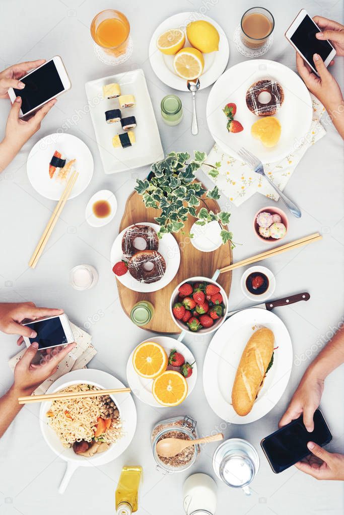 People using their smartphones at table with food