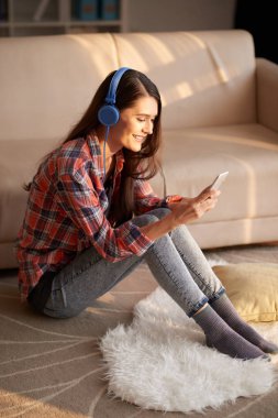 Katta oturan kız ve ve müzik uygulama smartphone kullanarak