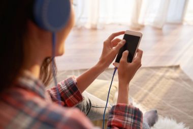 Akıllı, müzik dinlemek kadın omuz üzerinden görünüm