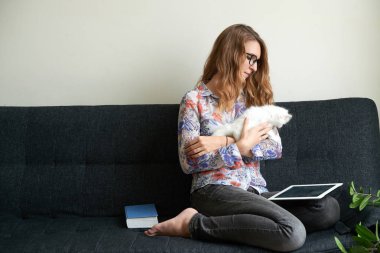 kadın evde kanepede otururken küçük kedi ile oynarken