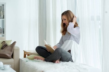 Genç kadın evde istirahat bir roman okuma