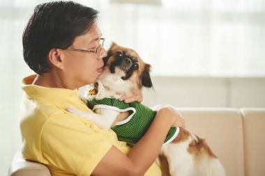 Orta yaşlı Asya adam sevimli köpeği sarılma