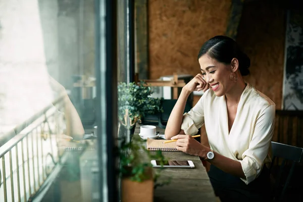 陽気なビジネス女性のカフェでコーヒーを飲んでいるとき ノートでメモを取る — ストック写真