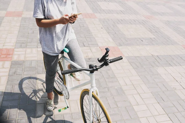 Kızın Akıllı Telefon Kontrol Bisiklet Üzerinde Resim Kırpılmış — Stok fotoğraf