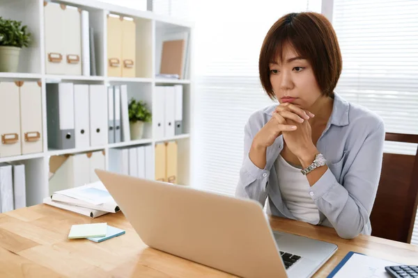 忧郁的日本女性商务主管在笔记本电脑屏幕上阅读信息 — 图库照片
