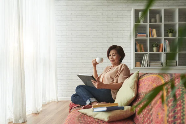 Vietnamese Senior Woman Drinking Tea Reading Book Tablet Computer — Stock Photo, Image