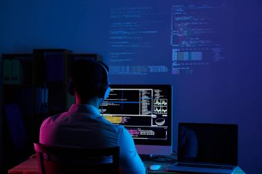 Gece geç saatlerde, kod üzerinde çalışan geliştirici arkadan görünümü