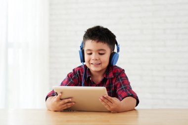 Tablet bilgisayar video izleme büyük mavi Kulaklığımda boy gülümseyerek