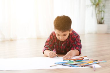 Işık Oda yerde yatan ve kalem ile çizim yetenekli küçük çocuk