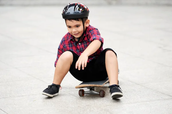 快乐的混合种族的男孩在头盔上坐在滑板 — 图库照片