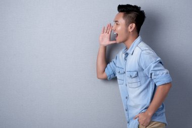 Asyalı adamın elini açık ağız ve bağırarak yakın tutarak profil görünümü