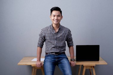 Ofis Masası oturma ve kamera için poz kendine güvenen genç işadamı