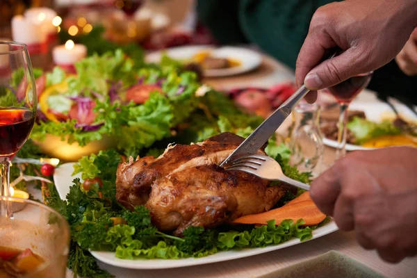 Close-up image of dinner guest cutting chicken