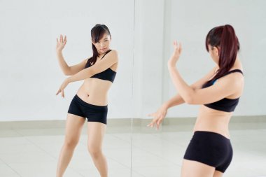 Geniş dans salonu, tam uzunlukta portre ayna önünde dans at kuyruğu ile çekici Asyalı kadın