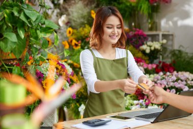 Tanınmayan müşteri Satınalmalar, çiçek Shop arka plan üzerinde iç ödemek için pretty Asya pazarlamacı için kredi kartı veren