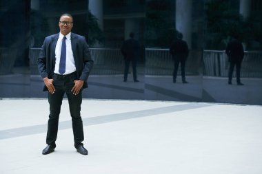 Tam uzunlukta gülümseyen ve açık havada kameraya bakarak emin Afrika-Amerikalı işadamı portresi