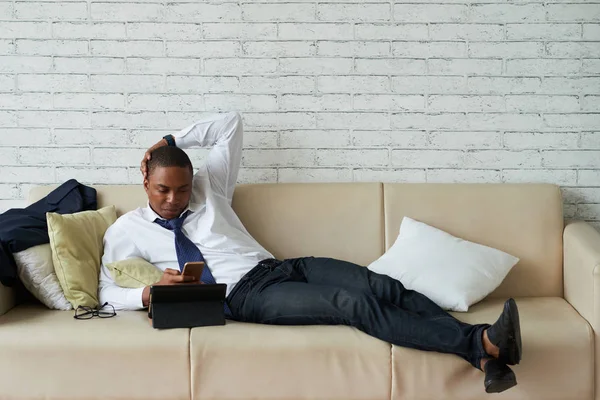 Bonito Empresário Descansando Sofá Com Smartphone Suas Mãos — Fotografia de Stock