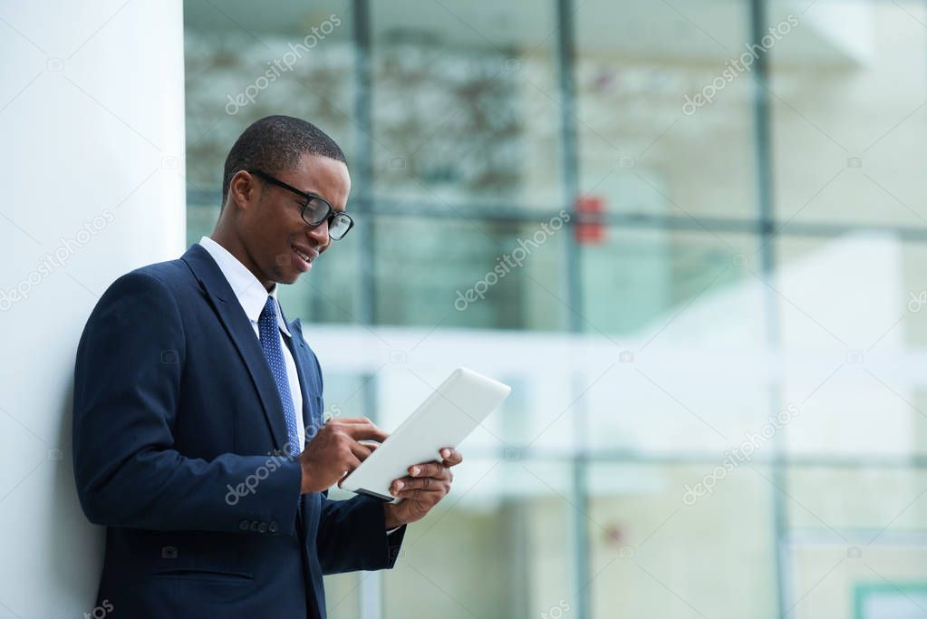 Smiling businessman reading information on tablet computer